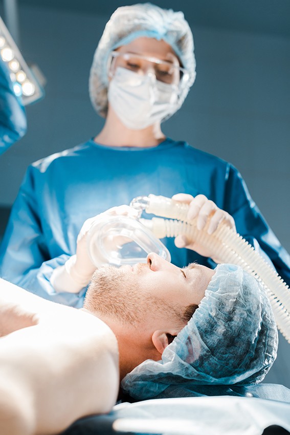 selective focus of nurse in uniform and medical cap putting mask on patient