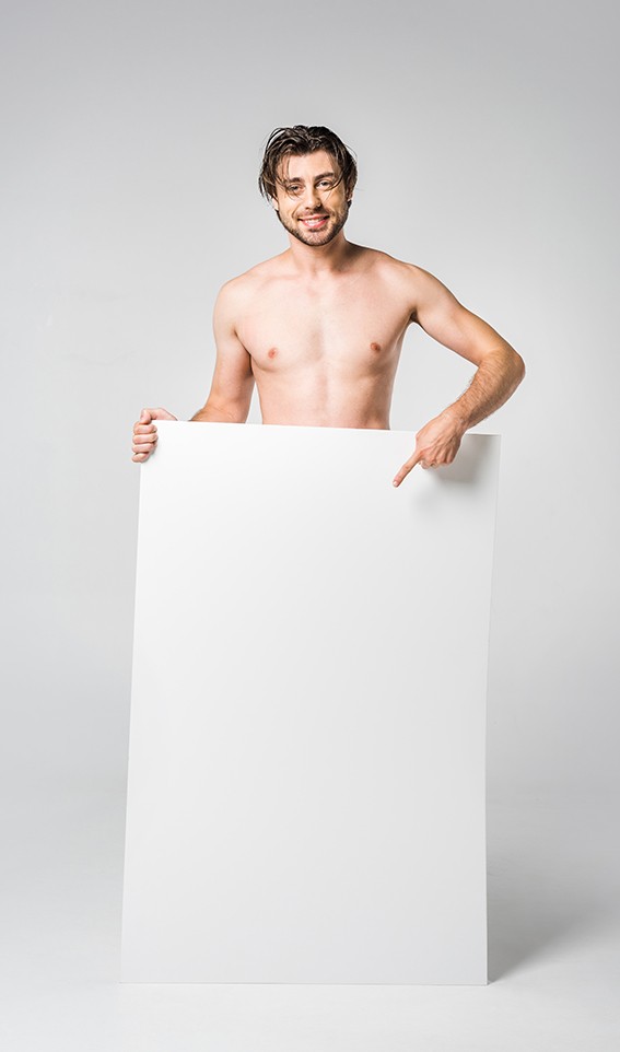 smiling handsome man pointing at blank banner on grey background